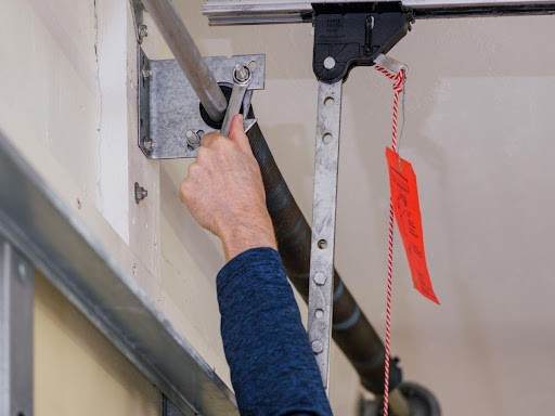 A close-up of a technician's hand performing a service on a garage door.