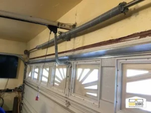 Garage door interior showing the emergency release mechanism and opener rail above the garage door.