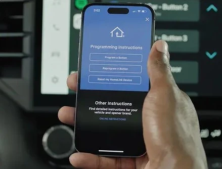 Hand pressing a garage door remote control button in front of a residential garage door